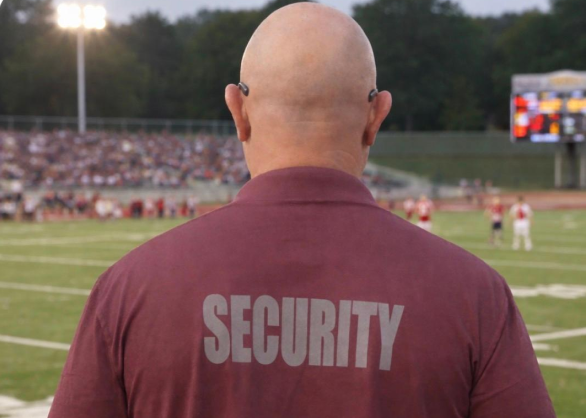 A security guard watches over a crowded outdoor event.